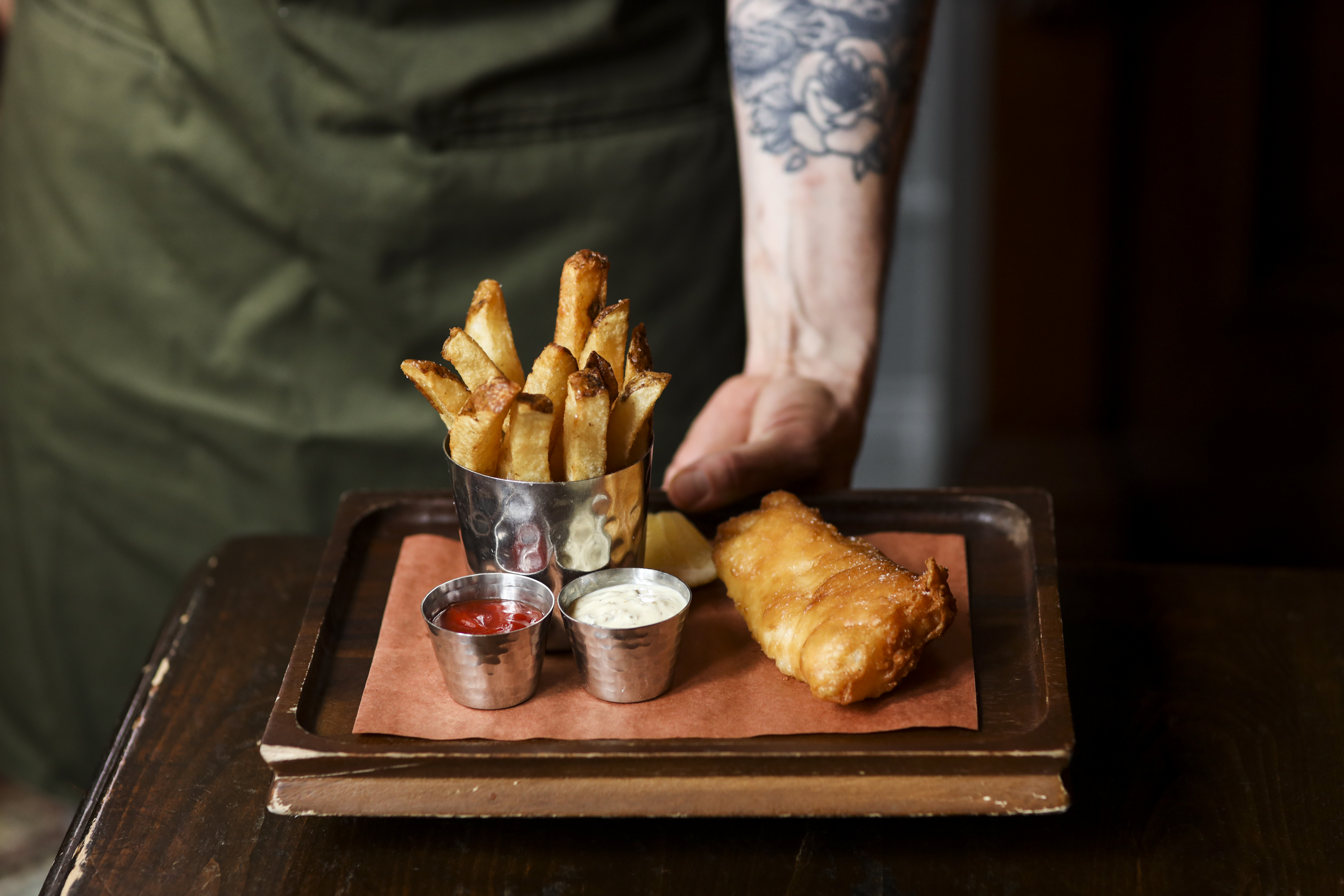 A server holding a tray of fish and chips